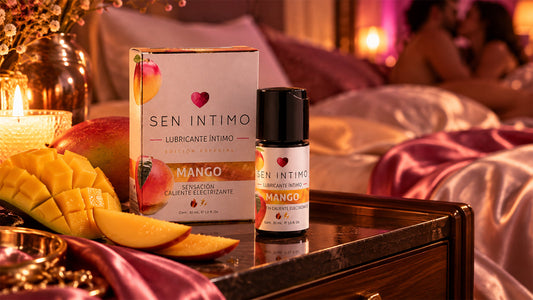 Lubricante Íntimo Electrizante Mango de Sen Íntimo junto a mango fresco, con una pareja al fondo