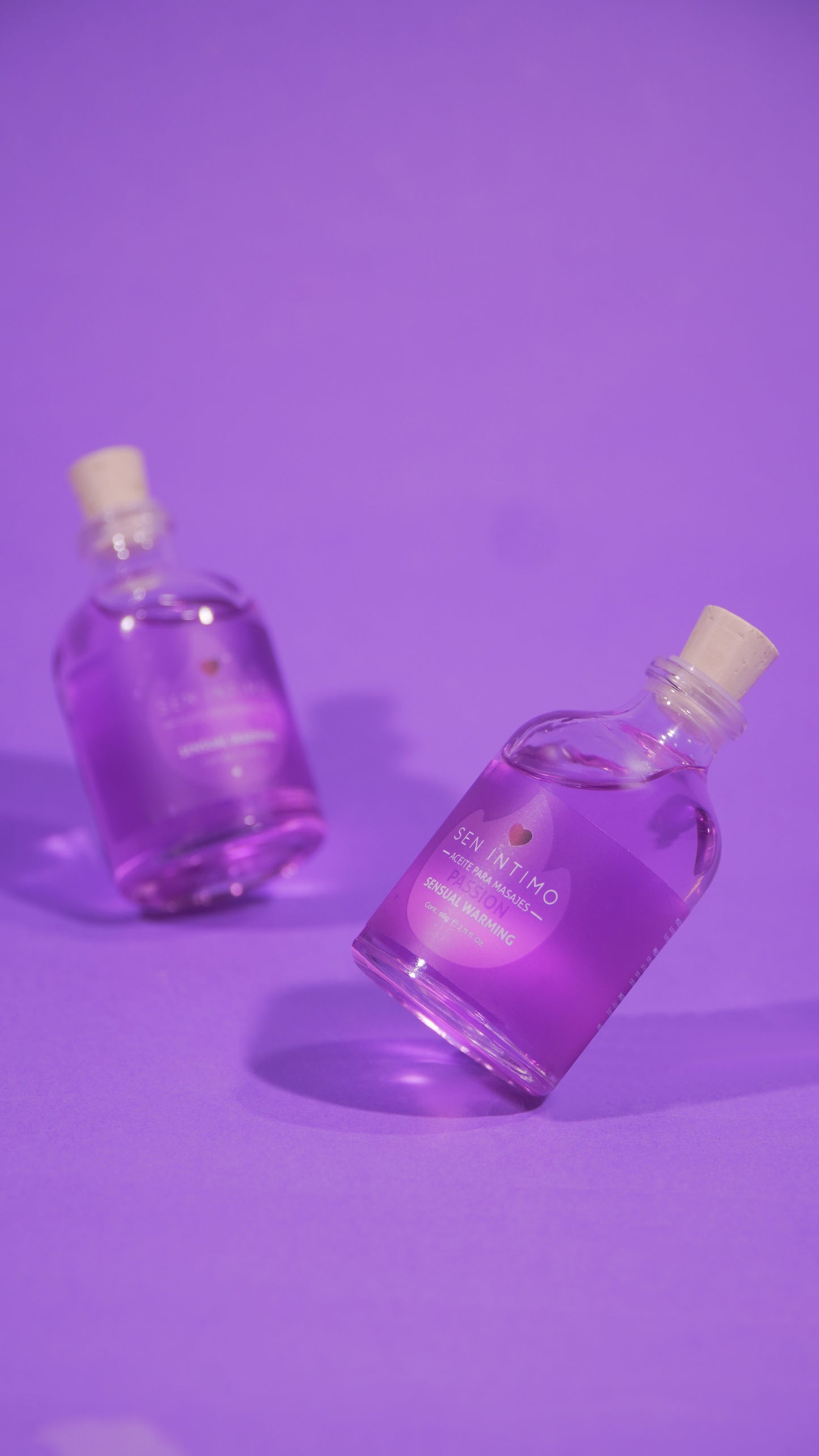 Aceite para masajes Sensual Warming Passion Sen Íntimo - dos frascos morados fondo lila foto publicitaria