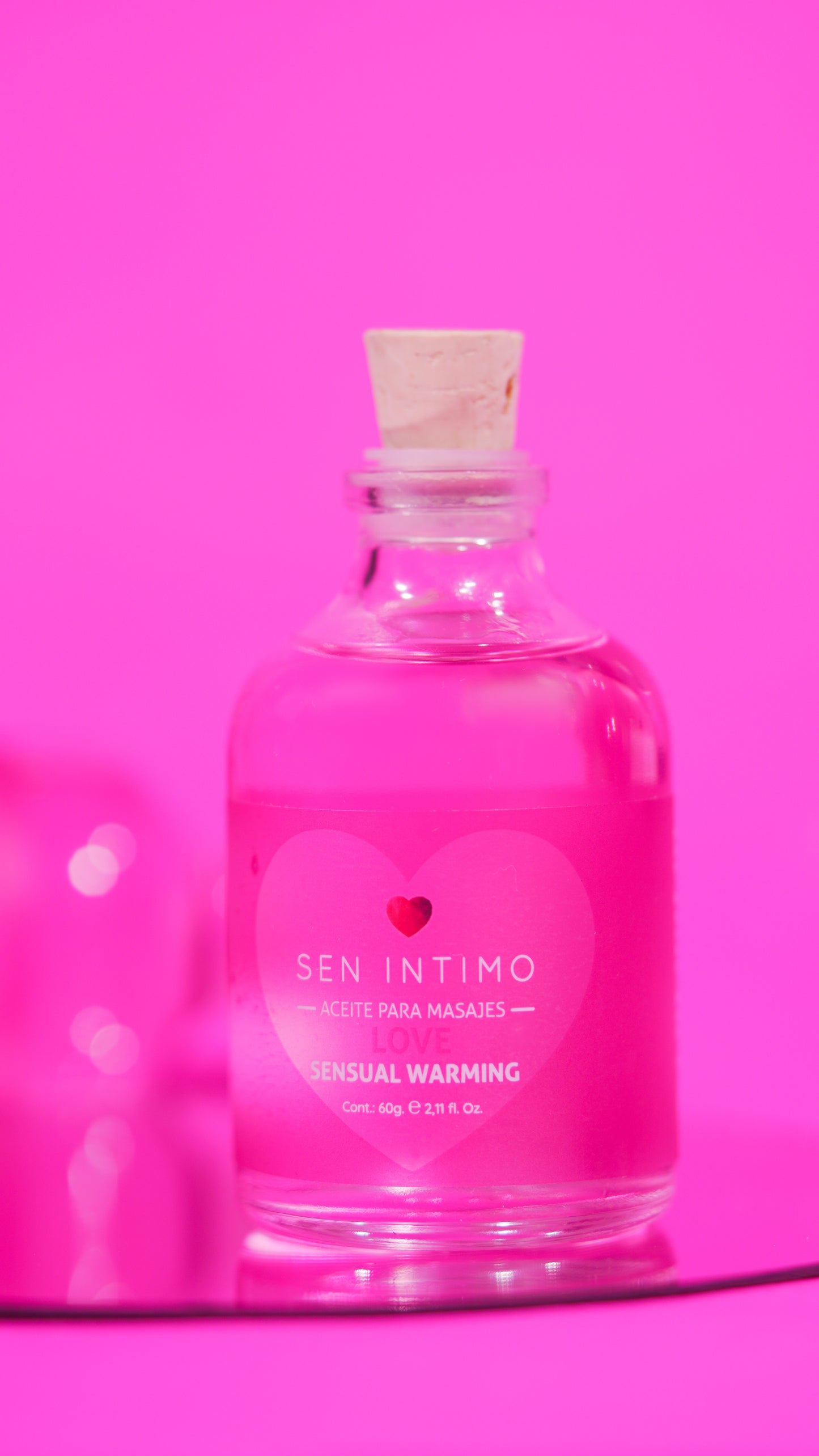 Aceite para masajes Sensual Warming Love Sen Íntimo - foto publicitaria frasco fondo fucsia